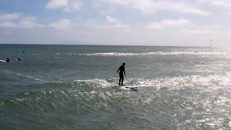 Surfer-in-silhouette-balances-to-ride-a-wave-on-a-surfboard---leading-aerial-view