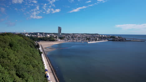 Aerial-panoramic-shot-of-Gdynia-Cityscape-with-Tower-and-beautiful-Baltic-Sea-with-Sandy-beach-during-blue-sky-and-sunlight---Poland,Europe