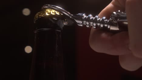 Slow-close-up:-Back-lit-beer-bottle-opened-with-chrome-bottle-opener