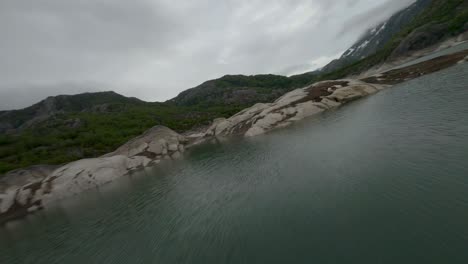 Aerial-flyover-Fjellhaugvatnet-Lake-with-rocks-in-Norway-during-grey-sky-in-Norway