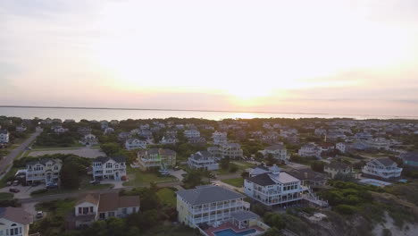 Drone-shot-of-beach-houses-on-the-coast-on-the-outer-banks-of-North-Carolina,-rising-and-tilting-downward