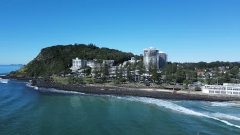 Surfers-enjoy-the-world-famous-Burleigh-Heads-surf-break-with-the-iconic-headland-and-township-rising-above