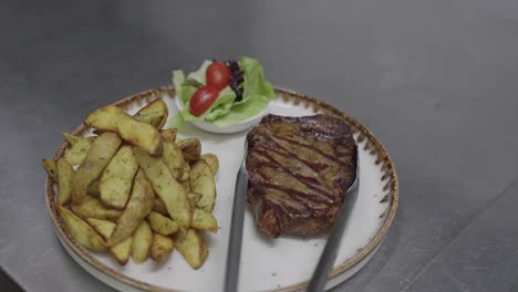 Chef-Serving-steak-meal-with-potato-wedges-on-a-plate