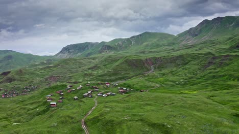 Aerial-–-Flying-Along-Sloping-Green-Hills-And-Small-Mountain-Villages