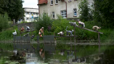 Künstlerische-Skulptur-Von-Katzen,-Die-über-Dem-Fluss-Auf-Dem-Zaun-Platziert-Sind