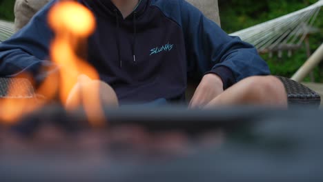 Teenage-boy-looking-at-friends-behind-campfire