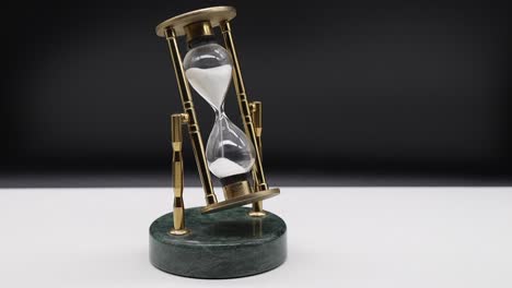 Hourglass-on-white-table-isolated-on-black-background