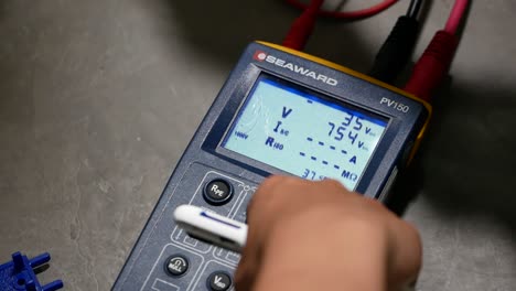 Asian-Hand-Using-Voltage-Meter,-Close-Up