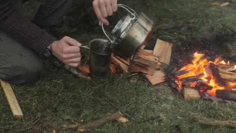 Pouring-tea-in-a-canteen-cup-from-an-Eagle-Kettle-in-the-forest-next-to-the-fire