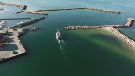 A-fishing-boat-moves-along-the-port's-equator-in-this-aerial-view-of-a-small-fishing-port-on-a-sunny-spring-evening