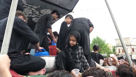 A-guy-and-a-young-girl-are-serving-sharbat-to-mourners-at-the-juloos,-or-parade,-of-Muharram,-also-known-as-Muharram-Ul-Haram