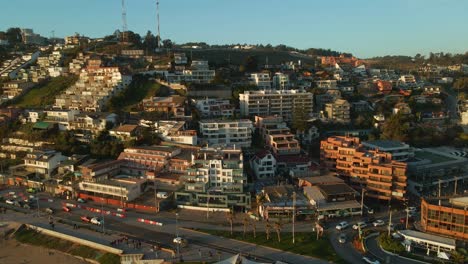 Aerial-view-rising-pan-left-above-Reñaca-coastal-city-buildings-on-Vina-Del-Mar-beach-resort-waterfront