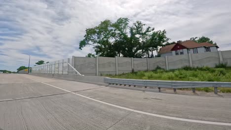 POV-while-driving-on-a-portion-of-Interstate-74-highway-that-is-run-through-the-Quad-Cities-in-Illinois-with-sound-barrier-walls-to-reduce-noise-in-residential-areas