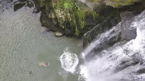 Junger-Klippenspringer-Springt-Von-Einem-Felsen-Neben-Einem-Wasserfall-Im-Fluss-Doubs,-Neuchatel,-Schweiz