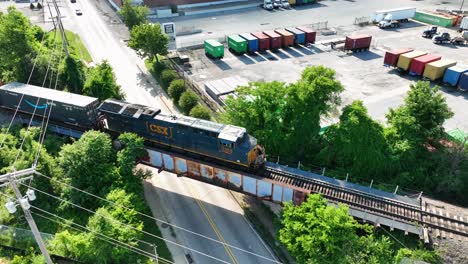 CSX-diesel-locomotive-engine-pulls-Amazon-Prime-freight-car-through-industrial-district-in-American-city