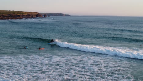 Surfers-enjoying-the-waves-by-the-beach-in-Cornwall,-UK