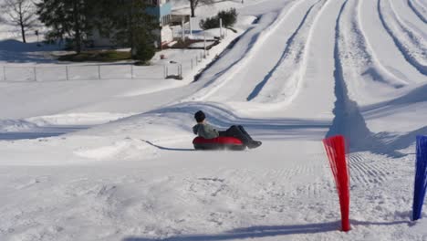 Slow-motion-shot-of-a-ski-resort,-man-sledding-on-the-snowy-track