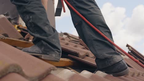 Close-up-to-a-worker-walking-on-rooftop,-roof-tile-removal