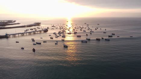Drone-video-of-boats-anchored-in-the-ocean-by-a-pier-during-sunset