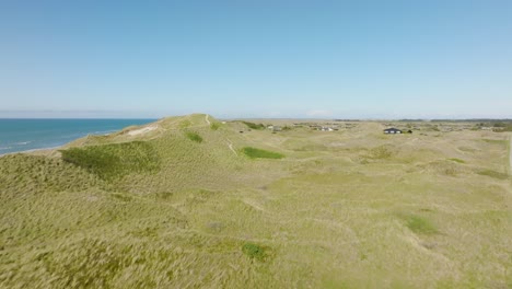 An-aerial-view-Small-houses-stand-between-high-and-grassy-sand-dunes