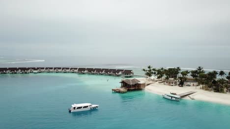 Drone-shot,-Maldives-island,-port-side,-water-villas-and-yachts,-blue-lagoon-and-a-mini-jungle