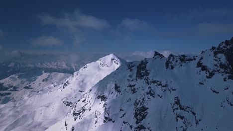Toma-Aérea-De-Drones-Volando-Sobre-Una-Alta-Cordillera-Cubierta-De-Nieve-Sobre-La-Ciudad-Turística-De-Verbier,-Suiza