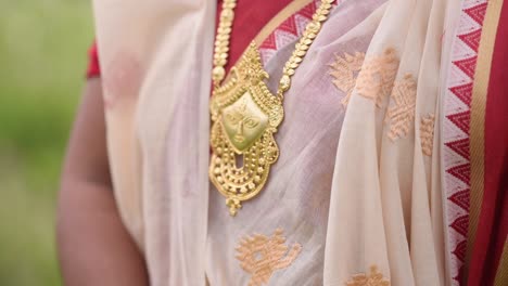 Indian-woman-wearing-a-gold-necklace-of-a-human-face-of-Goddess-Durga,-close-up