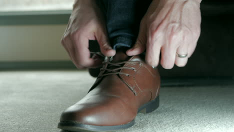 Man-putting-on-brown-dress-shoe