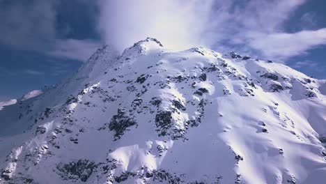 Toma-Aérea-De-Un-Pico-Nevado-Blanco-Entre-Los-Alpes-Y-Las-Montañas-Sobre-La-Ciudad-Turística-De-Verbier,-Suiza