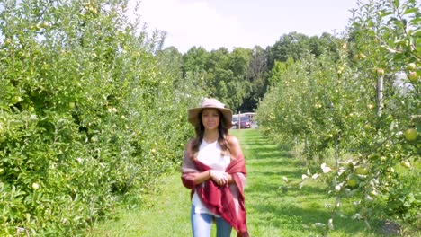Woman-walks-towards-the-camera-through-an-orchard
