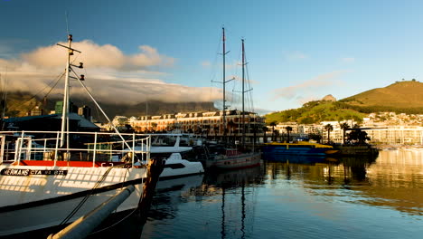 Boats-moored-in-Cape-Town-harbor,-view-of-cloud-covered-Table-Mountain