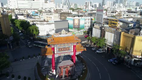 Tilt-down-drone-Chinatown-Gate,-Yaowarat-Road-and-skyline-Bangkok,-Thailand