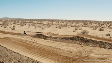 Aerial-drone-footage,-motocross-bike-catching-air-in-slow-motion,-Mojave-Desert
