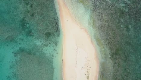 Aerial-tracking-shot-of-one-woman-on-sandbar-surrounded-by-amazing-waters-on-Siargao,-the-Philippines