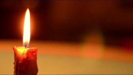 Single-candle-flickers-against-dark-background