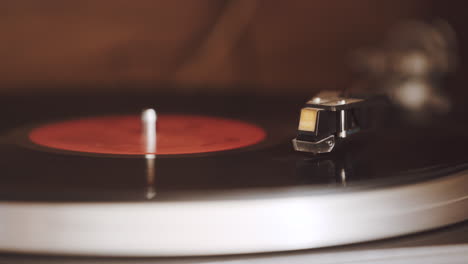 An-old,-dusty-record-player-is-playing-a-black-vinyl-record-with-a-red-label-at-33-1-3-rpm