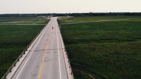 Drone-shot-of-single-motorcycle-riding-across-bridge