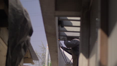 Man-welding-a-metal-vigge-on-the-roof-of-a-house,-in-4k-slowmotion