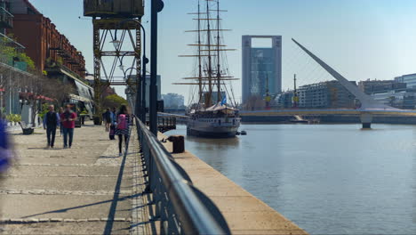 People-walking-and-photographing-in-Madero-Port-with-Sarmiento-Frigate-and-Woman’s-Bridge-in-background-at-daytime-time-lapse