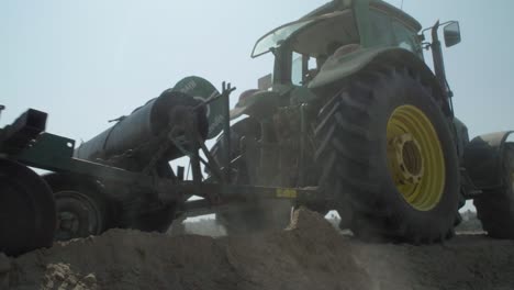 Tractor-pulling-black-plastic-mulch-across-farmland-field-in-Huelva,-Spain