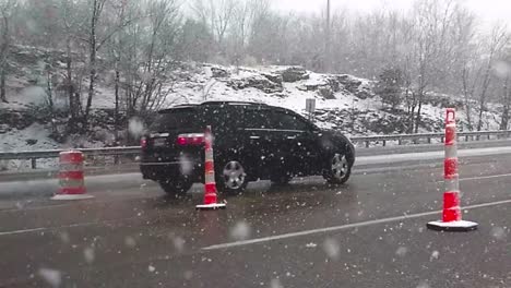 SUV-driving-through-a-snowy-road-with-safety-cones-in-Sellersburg,-Indiana,-SLOMO