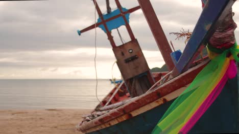 Close-up-dolly-shot-of-wooden-Thai-fishing-boat-on-the-beach,-during-sunrise