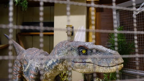 Un-Dinosaurio-Velociraptor-Robótico-Rugiendo-Dentro-De-Un-Robot-Jaula