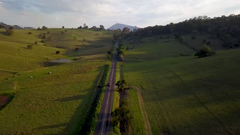 Car-driving-through-green-hills,-Queensland,-Australia