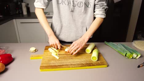 Woman-cutting-leeks-over-a-wooden-table