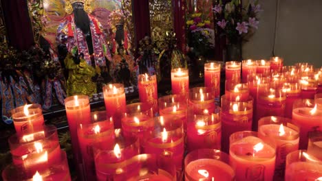 Slow-motion-shot-of-red-candles-in-front-of-religious-figure-at-Longshan-Temple-in-Taipei,-Taiwan