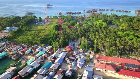 Aerial-flight-over-local-village-and-clear-ocean-in-Malaysia,-medium-shot-moving-towards-island-in-slow-motion
