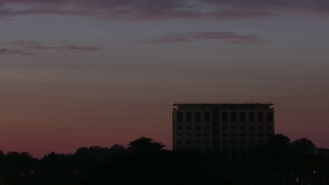 Fast-dusk-to-dawn-timelapse-of-a-tall-building-with-trees-below