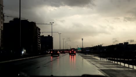 Windshield-first-person-view-of-road-traffic-during-early-morning-sunrise-with-clouds-under-heavy-rain-in-a-highway-of-Dubai,-United-Arab-Emirates-on-November-26,-2018