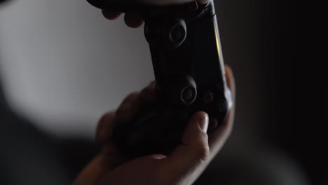 Male-hands-in-close-up-concept-pressing-buttons-of-black-playstation-controller-vue-joystick-in-slow-motion